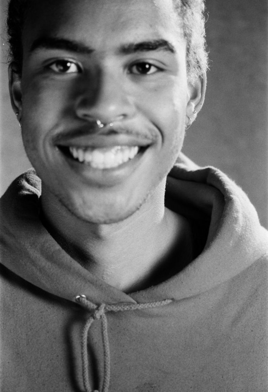 Black and white portrait photo of writer/director of SOYBOY Moo Renzaho: black male, short curly hair, septum piercing, wearing a hoodie