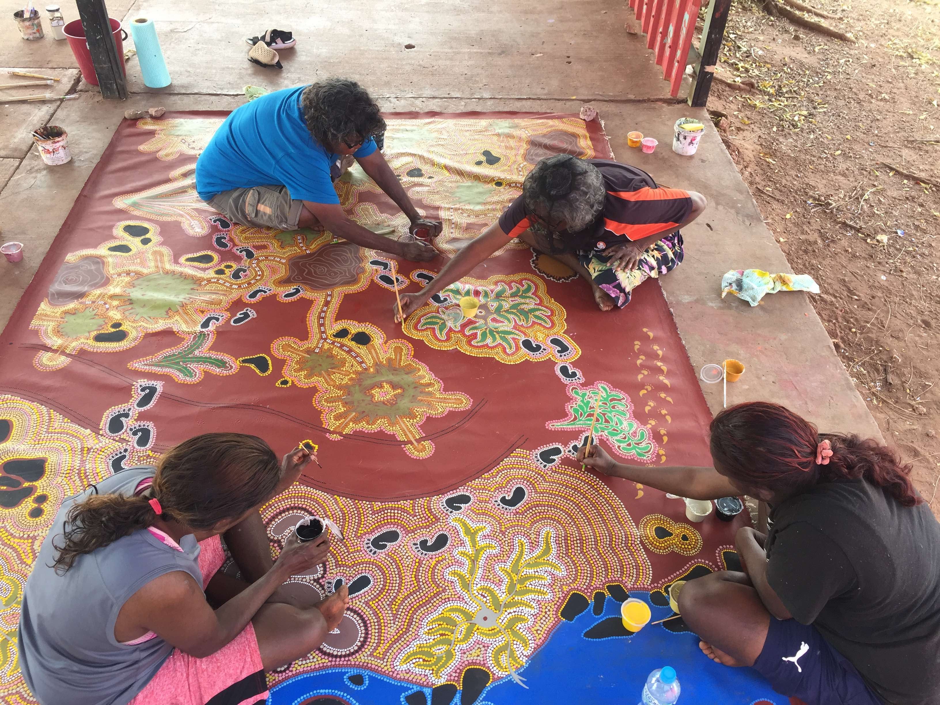 Gurindji artists painting a large collaborative work about collecting bush medicine to treat babies