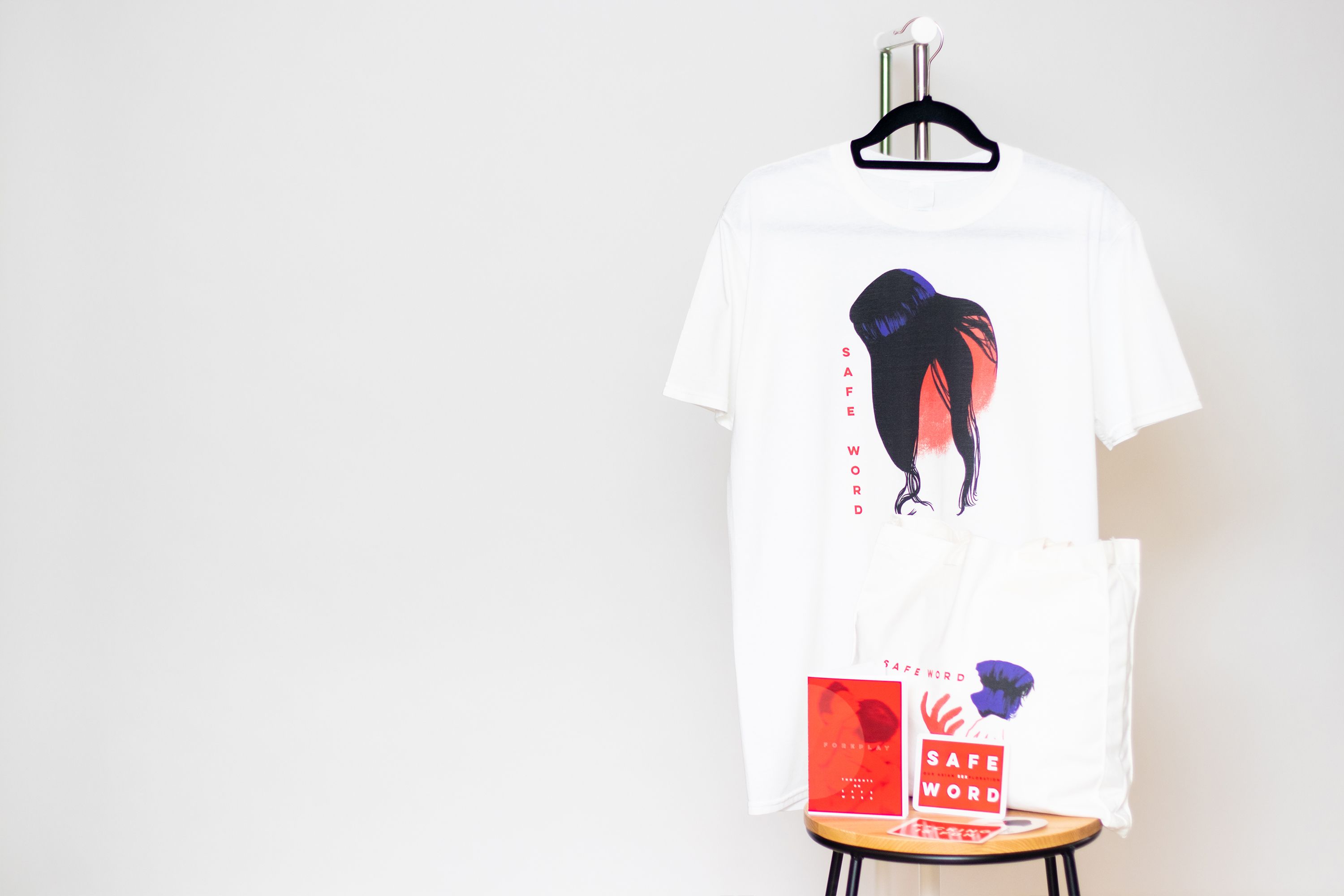 Tier 4 Merchandise for those who pledge $75 or more. Image displays the Safe Word tee, tote bag, zine and sticker set.