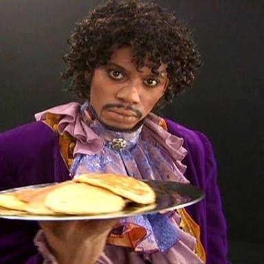 Funny image of comedian Dave Chappelle dressed as Prince, holding a platter of pancakes